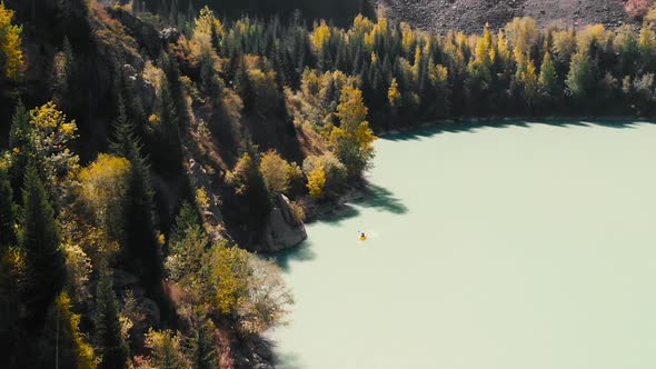 Man is Paddling on Raft Boat in the Mountain Lake