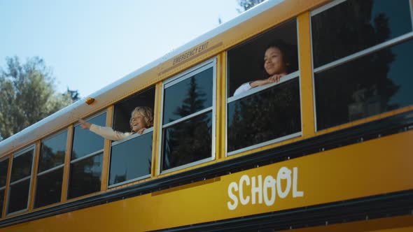 Two Multiethnic Pupils Looking Out School Bus Window