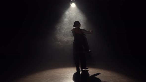 Man and Woman Perform Latin Dance in Darkness with Overhead Light and Smoke