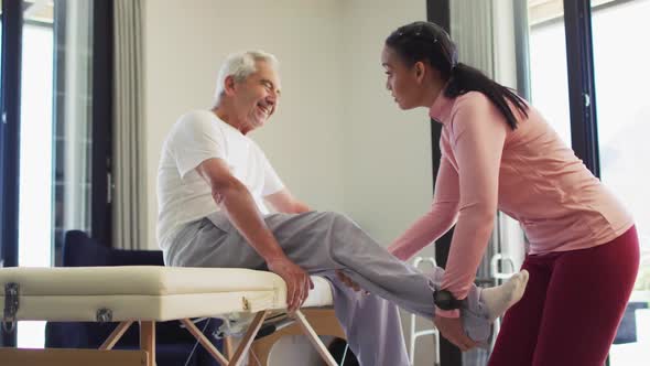 Video of biracial female physiotherapist examining caucasian senior man