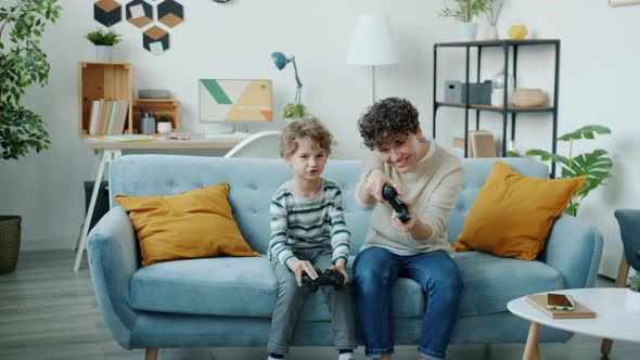 Slow Motion of Young Woman and Son Playing Video Game Together in Apartment