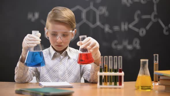 Little Nerd Comparing Liquids in Flasks and Writing Reaction Results, Innovation