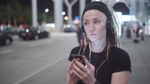 Young Attractive Hipster Woman Use Smartphone Listening Music and Dance on Street at Night