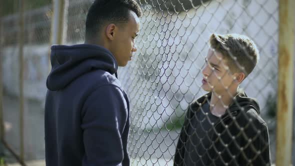 Two Boys of Different Nationalities Talking, Rich and Poor Separated by Fence