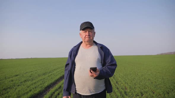 Mature Farmer Examining Soil and Using Smartphone Checking Report of Agriculture in a Field