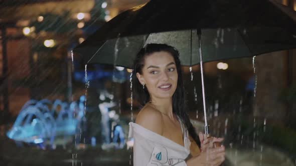 Wet Girl Turning Around with Umbrella and Looks at Camera