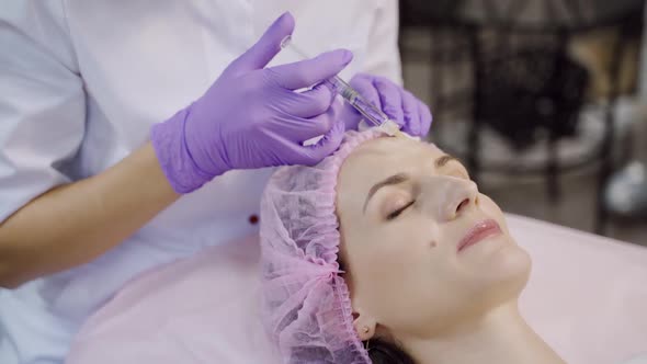 A beautiful woman is on the procedure of facial rejuvenation. Beautician makes mesotherapy