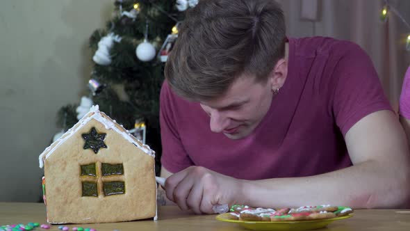 A Guy Decorates a Christmas Gingerbread House