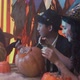 Two Girls and a Guy in Creepy Halloween Costumes are Sitting at a Table Chatting and Carving Faces - VideoHive Item for Sale