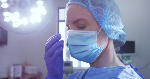 Female caucasian surgeon with face mask, surgical cap and protective clothing in hospital