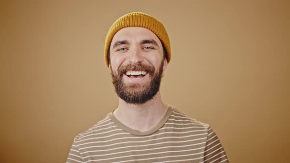 Young Man in Mustard Hat Smiles and Blows Kiss Closeup