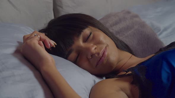 Smiling Woman Sleeping Peacefully in Bed at Night