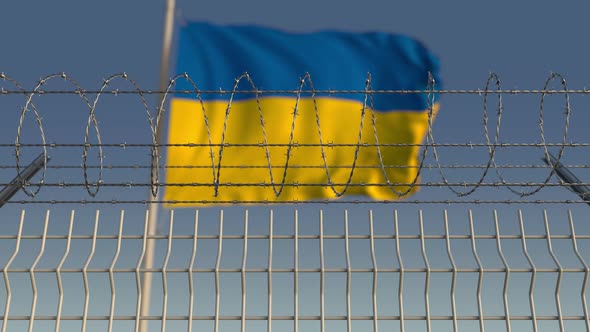 Waving Flag of Ukraine Behind Barbed Wire Fence