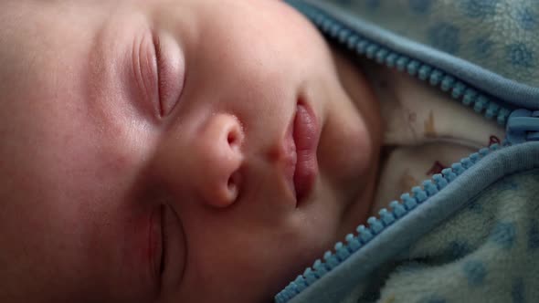 Closeup Newborn Baby Face Portrait Early Days in Macro Sleeping And Smiling Through Dream in Blue