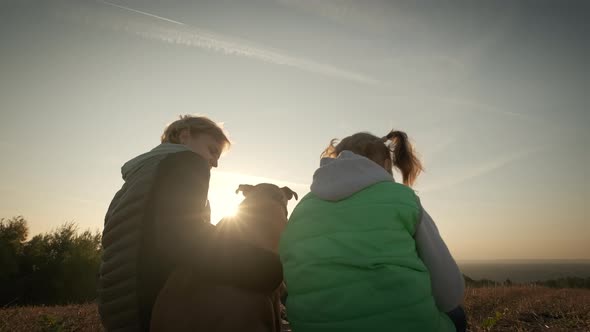 Silhouettes of Woman with Little Daughter and Pet Dog Sitting During Amazing Sunset