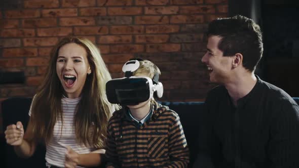 Portrait of Cheerful Parents and Their Son Playing Video Games in Virtual Reality Glasses. Happy