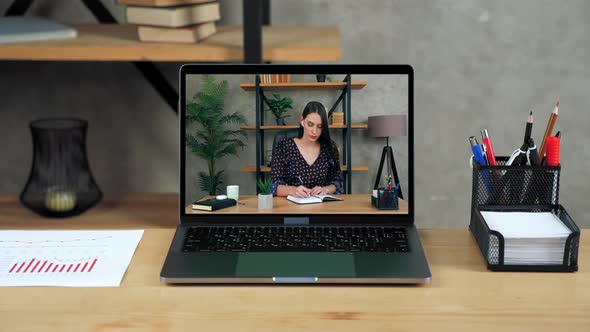 Laptop Standing on Table Display with Businesswoman in Office Writes in Notebook