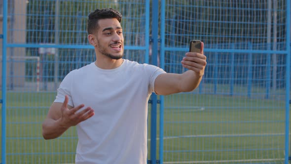 Young Sports Blogger Indian Guy in Sportswear Looking at Smartphone Camera Records Broadcasts From