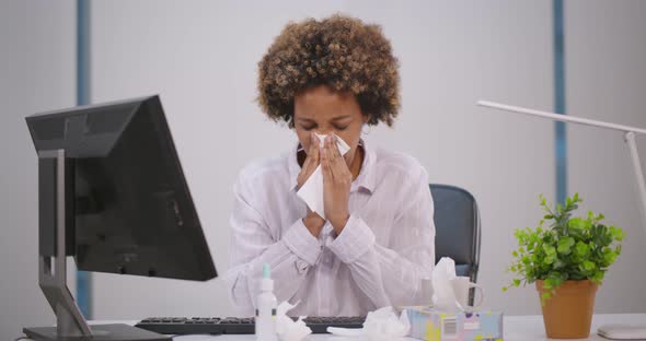 Unhealthy Female African Employee Coughing or Sneezing While Working in Workplace in Office