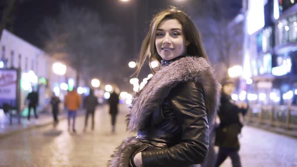 Young Beautiful Pretty Woman Smiling and Posing at City Street in the Night Against Evening Lights