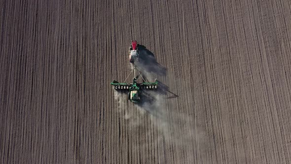 Aerial view of tractor with harrow system plowing ground on cultivated field