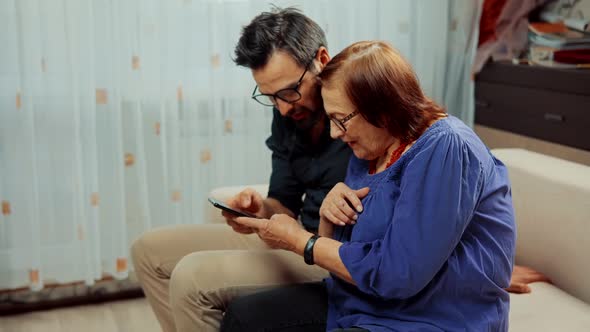 Senior Grandmather With Grandson Looking On Smartphone. Grandson Teaching Grandma Using Mobile Phone