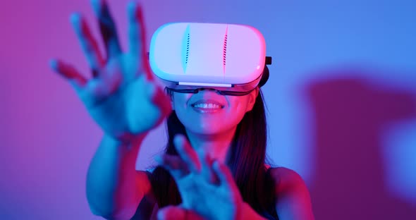 Woman playing with VR headset with cyber lighting