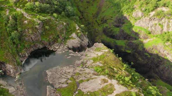 Drone Over Waterfall Cascading Down Into Rocky Valley