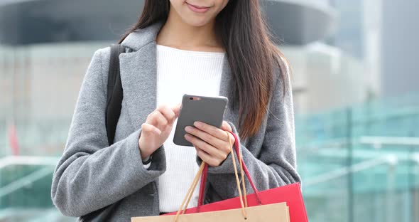 Woman use of mobile phone and holding shopping bag