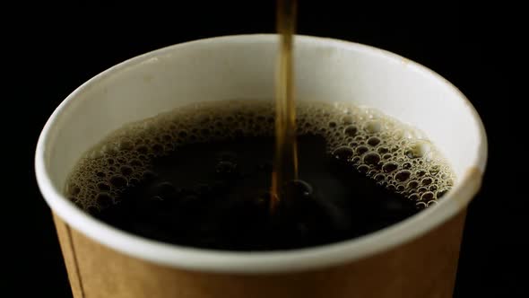 The stream pours into a glass of coffee, and the bubbles burst.