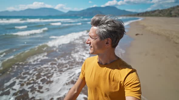 Close Up Portrait of Happy Middle Aged Greyhead Man Walks at Sandy Sea Coast