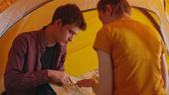 Woman and Man are Sitting in Tent and Looking at Map