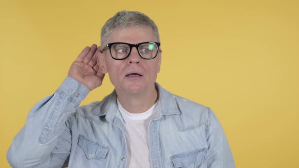 Casual Senior Man Listening Secret, Isolated on Yellow Background