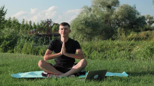 Man sitting on yoga mat in lotus position and raising hands up. Meditation