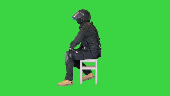 Policeman Wearing Face Mask and High Tech Helmet Sitting Waiting Thinking on a Green Screen Chroma