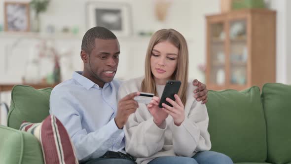 Mixed Race Couple Online Shopping on Smartphone at Home