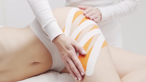 Therapist is applying kinesio tape to female body. Physiotherapy, kinesiology and recovery.