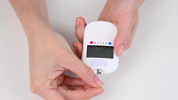 Woman Measures Blood Sugar Level with a Glucometer