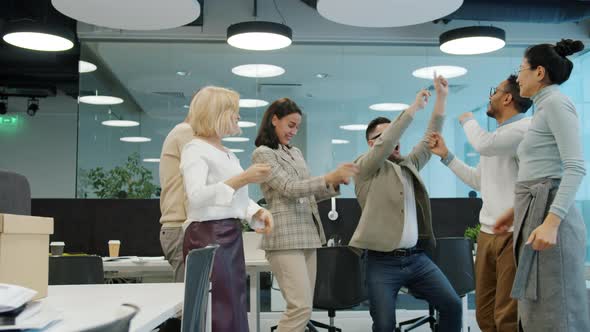 Slow Motion of Cheerful Coworkers Dancing in Shared Office Having Fun Together