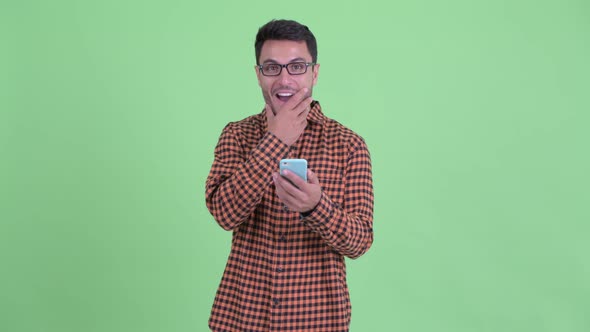 Happy Young Hispanic Hipster Man Using Phone and Looking Surprised