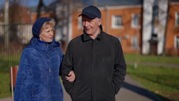 Elderly Married Couple is Walking on Street in Sunny Winter Day Going Hand in Hand