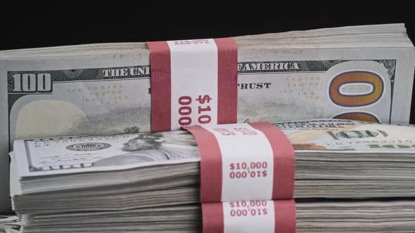 Bundles of Dollars Lying on a Pile of Money and Rotate on Black Background