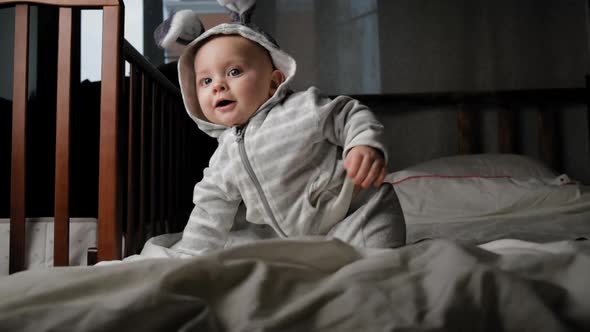 Cute Toddler Boy with Bunny Ears Crawling on Bed