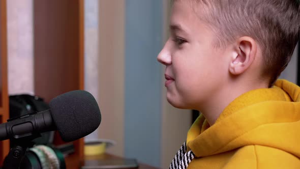 Smiling Blogger Boy Talking Into Microphone Vlogging for Kids in Pro Studio