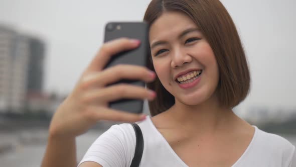 Beautiful young Asian woman having video chat using smartphone.