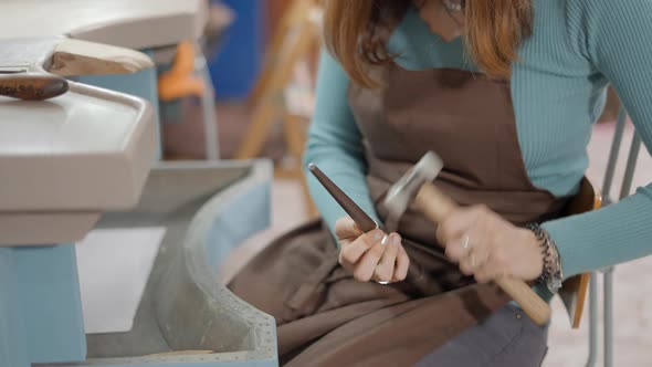 Woman Jeweller Hammering A Ring At Her Workshop Place