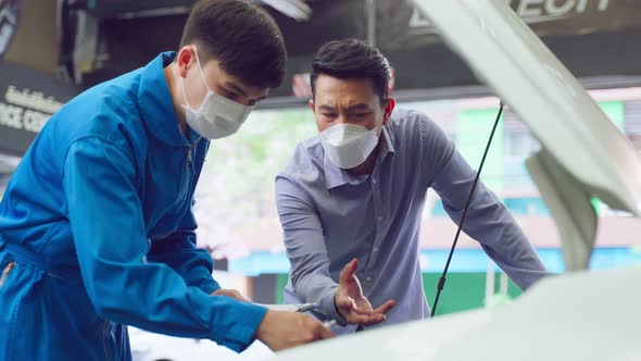 Asian automotive mechanic listen to client man explain car condition.