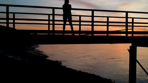 Silhoutte of young woman at sunset. Antwerp International Port. Drone Shot