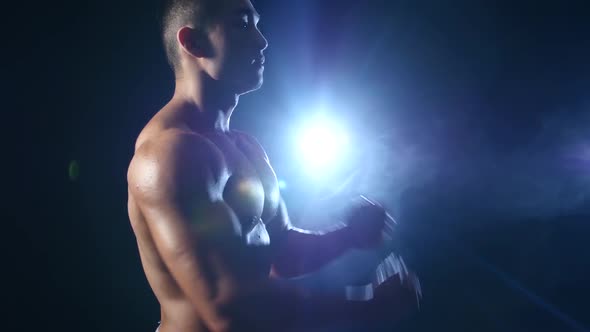 Asian Bodybuilder Demonstrates His Body, Strength and Endurance. Black Smoke Background