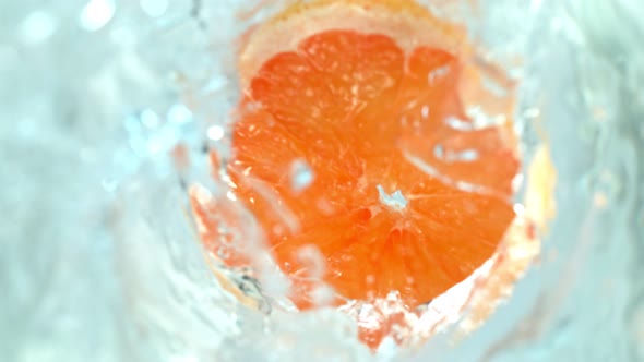 Super Slow Motion Shot of Falling Grapefruit Slices Into Water Vortex at 1000Fps.